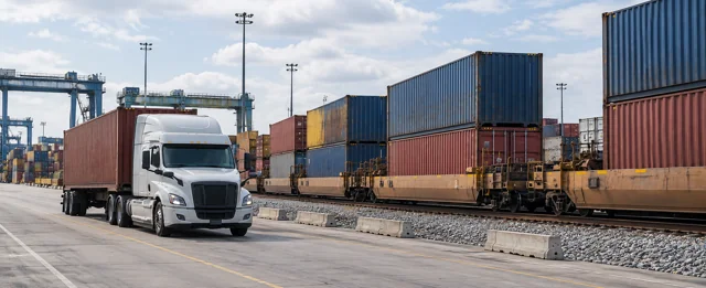 Container truck alongside a double-stack freight train