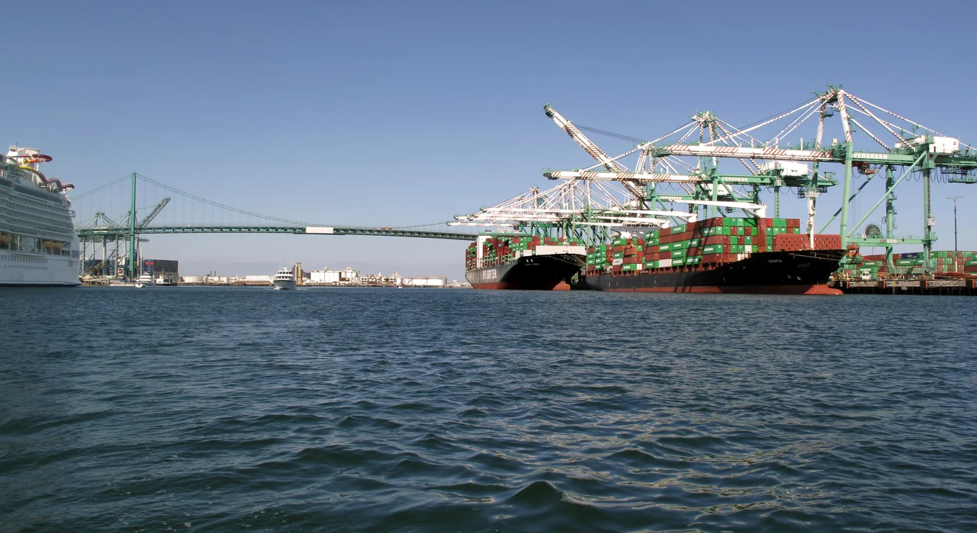 Container ships and cranes at the Port of Los Angeles, with the Vincent Thomas Bridge behind them.