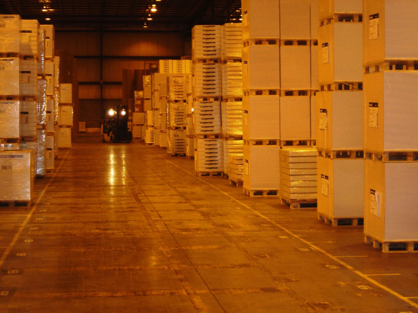 Palletized goods stacked inside an Allentown warehouse, with a forklift operating down the aisle.